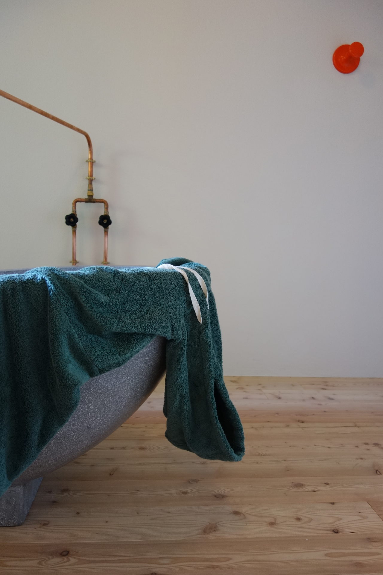 Teal poncho hanging on a black beach hut